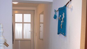 A hallway with a white door and a blue knitted item hanging on the wall. - Apartment Monima - Apartment (Bergen auf Rügen)