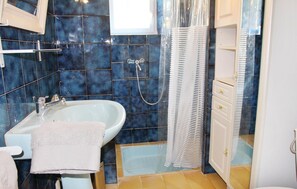 Bathroom features a white sink, mirror, and striped shower curtain, with a towel hung on the sink and a cabinet with a gold handle.