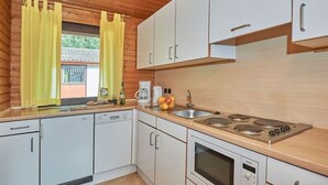 Una cocina con armarios blancos, una estufa Bosch y una ventana con cortinas amarillas.