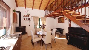 A spacious living area with a wooden staircase, a dining table with chairs, a piano, and a kitchen with a sink and cabinets. - 1 bedroom nice home in Smokvica (Smokvica)