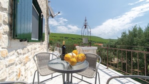 A balcony with a table, chairs, and a view of green hills. - 1 bedroom nice home in Smokvica (Smokvica)