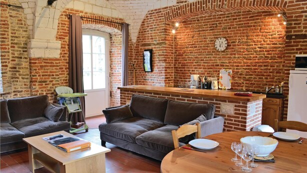 A cozy living room with a brick wall, a sofa, a coffee table, and a dining area with a wooden table and chairs. - Awesome home in Gouy Saint Andre with WiFi (Gouy Saint Andre)