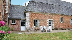 A brick building with a white door, two windows, and a small outdoor seating area with white chairs. - Awesome home in Gouy Saint Andre with WiFi (Gouy Saint Andre)