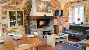 A cozy living room with a stone fireplace, a wooden dining table, and a comfortable sofa. - Awesome home in Gouy Saint Andre with WiFi (Gouy Saint Andre)