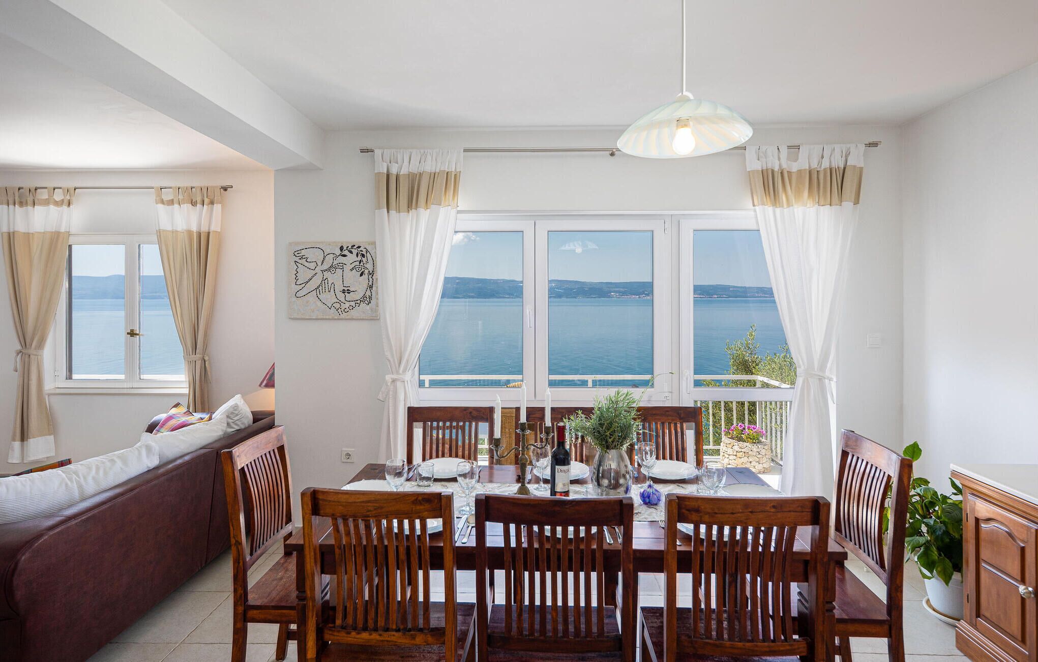 A dining area with a table set for four, a sofa, and a view of the sea.
