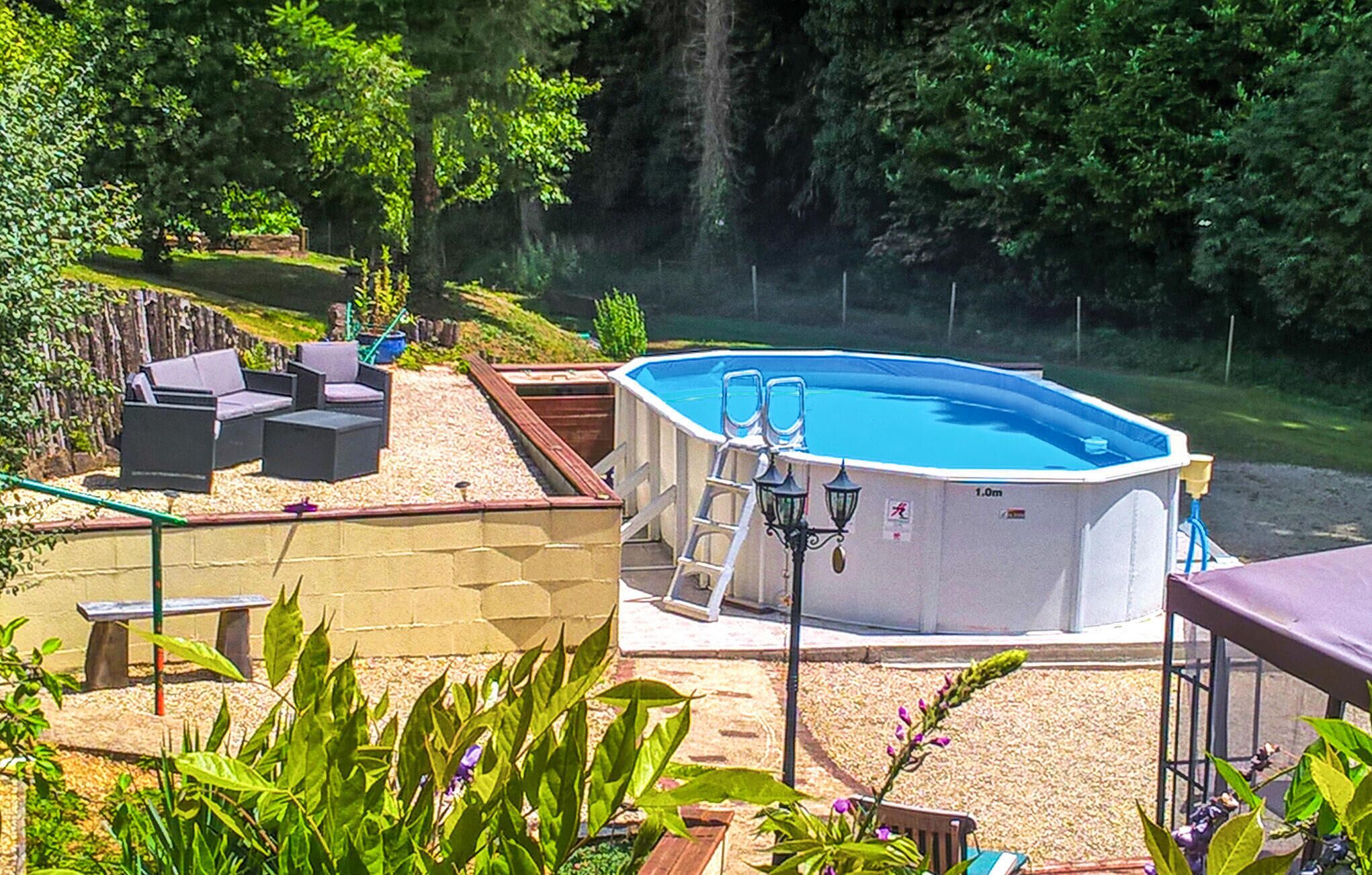 Una piscina al aire libre con escalera, rodeada por una terraza con mobiliario y plantas.