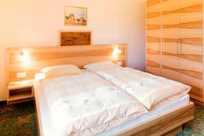 Un lit double avec une tête de lit en bois, deux tables de chevet, une armoire en bois et un tableau encadré accroché au mur.