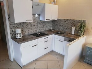 A modern kitchen with white cabinets, a wooden countertop, a built-in stove, and a sink.