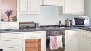 A kitchen with white cabinets, a stove, a microwave, and a toaster.