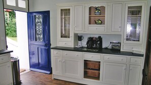A kitchen with white cabinets, a blue door, and a coffee maker.
