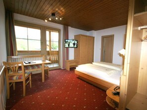 Ein Schlafzimmer mit einem Bett, einem Holztisch, einem Fernseher und einem Fenster.