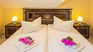 Una habitación de hotel con dos camas, mesitas de noche con lámparas y almohadones decorativos.