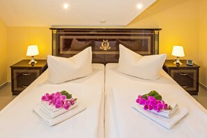 Una habitación de hotel con dos camas, mesitas de noche con lámparas y almohadones decorativos.