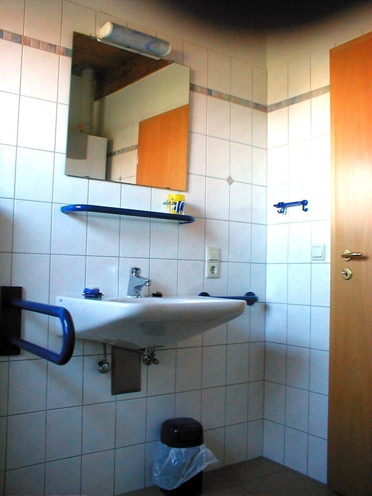 A bathroom with a white sink, a mirror, and a wooden door.