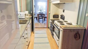 A narrow kitchen with a stove, sink, and a dining area visible through an open door. - Lovely home in Annerstad with sauna (Annerstad)