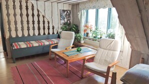 A cozy room with a blue sofa, two white chairs, a wooden table, and a red rug. - Lovely home in Annerstad with sauna (Annerstad)