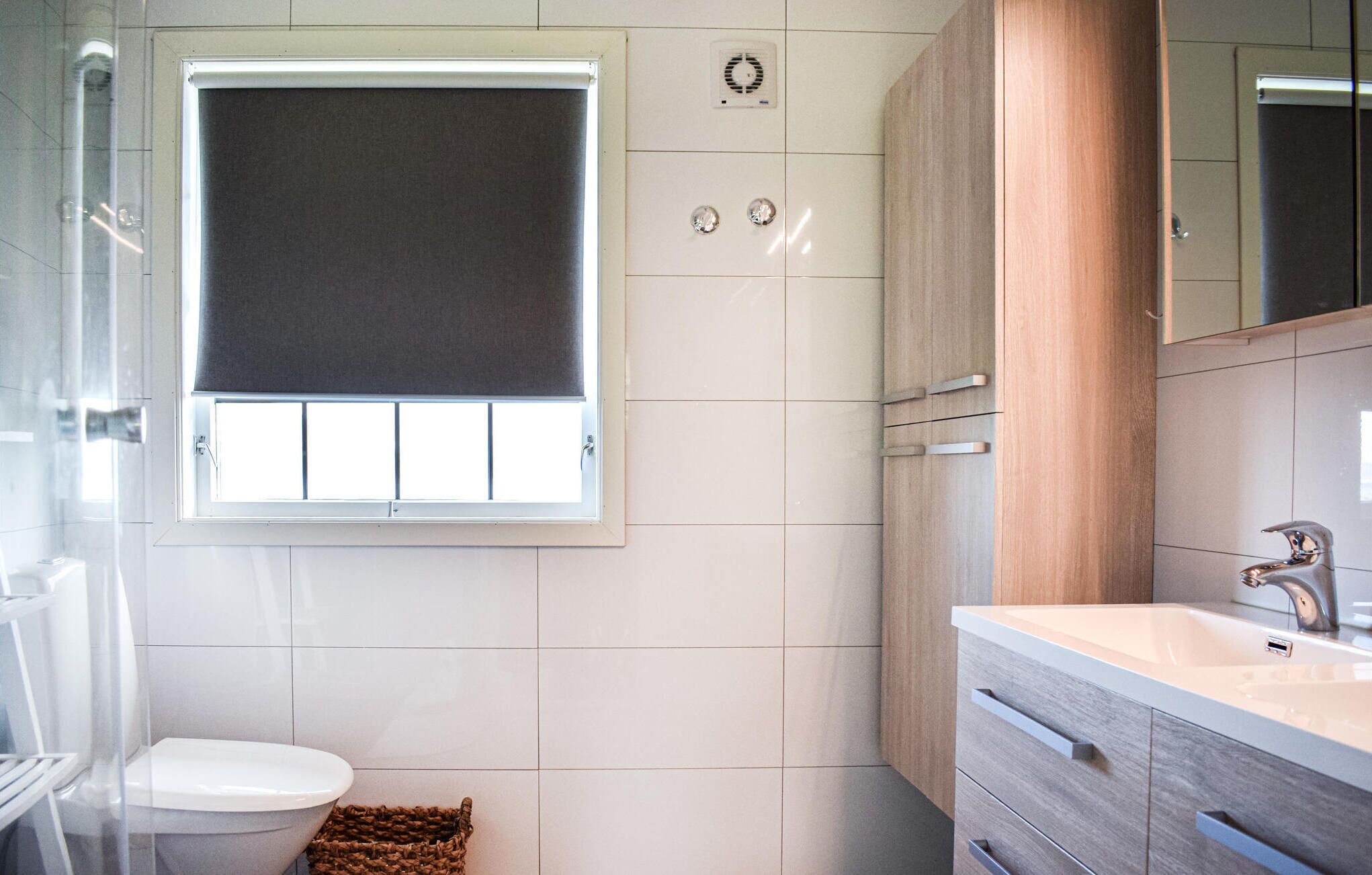 Een moderne badkamer met toilet, wastafel en raam.