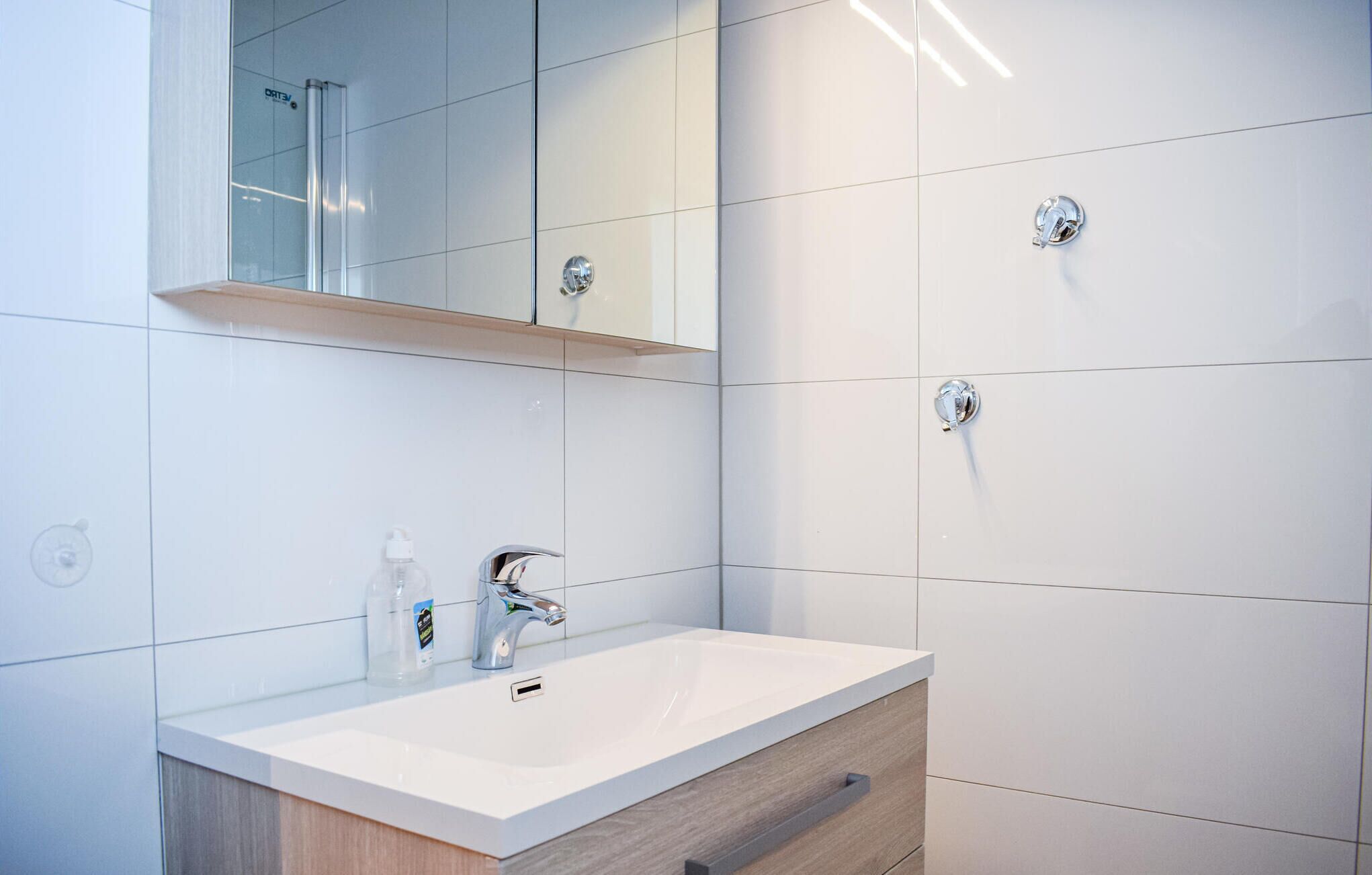 A modern bathroom with a white sink, chrome faucet, and a mirror above.