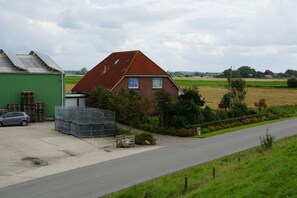 Une maison de campagne avec un toit rouge, une remise verte et une voiture garée devant.