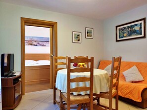 Enjoy a meal for two at the dining table, accompanied by a comfortable chair and a sofa with a cushion.