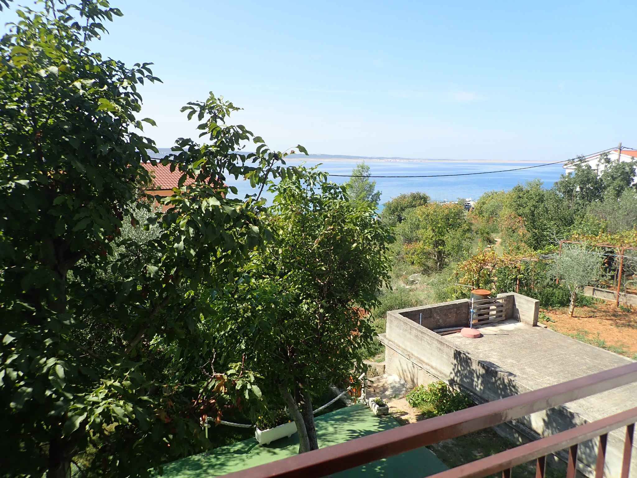 Un balcon offrant une vue sur un paysage côtier, avec des arbres et une étendue d’eau visible au loin.