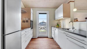 Una cocina moderna con armarios blancos, un lavamanos de acero inoxidable y piso de madera.