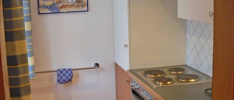 A compact kitchen with a stove, oven, and white cabinets.