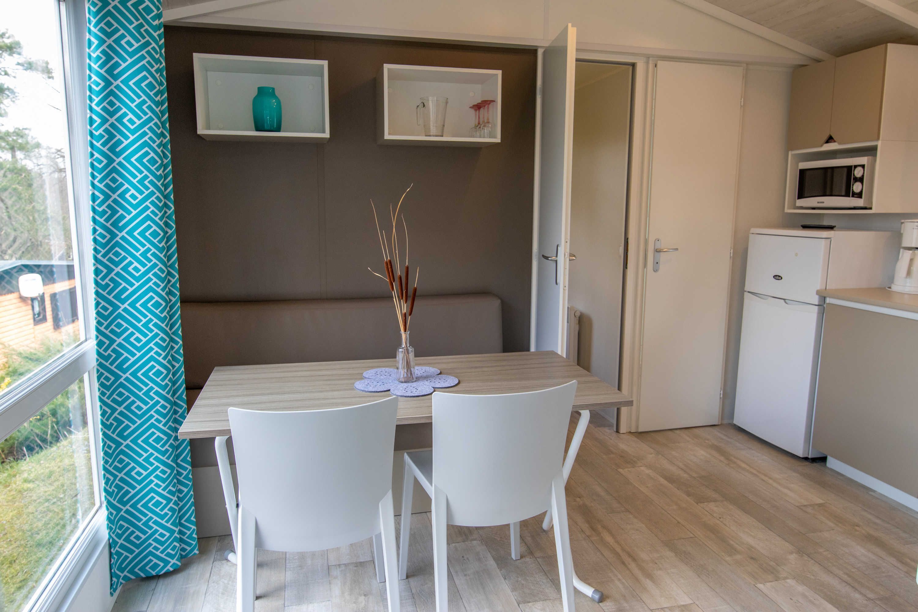 Eine kompakte Küche mit Mikrowelle, kleinem Kühlschrank und einer Essecke mit Tisch und Stühlen.