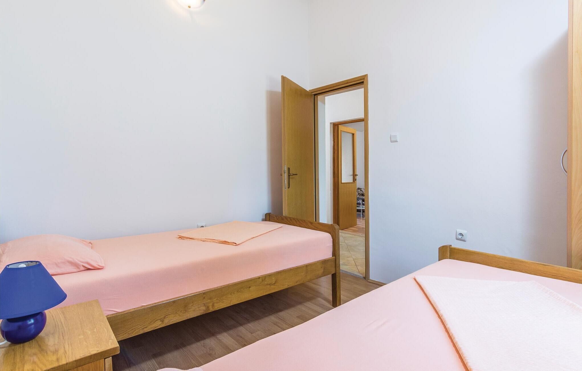 Een kleine, schone kamer met twee eenpersoonsbedden, een houten deur en een spiegel.