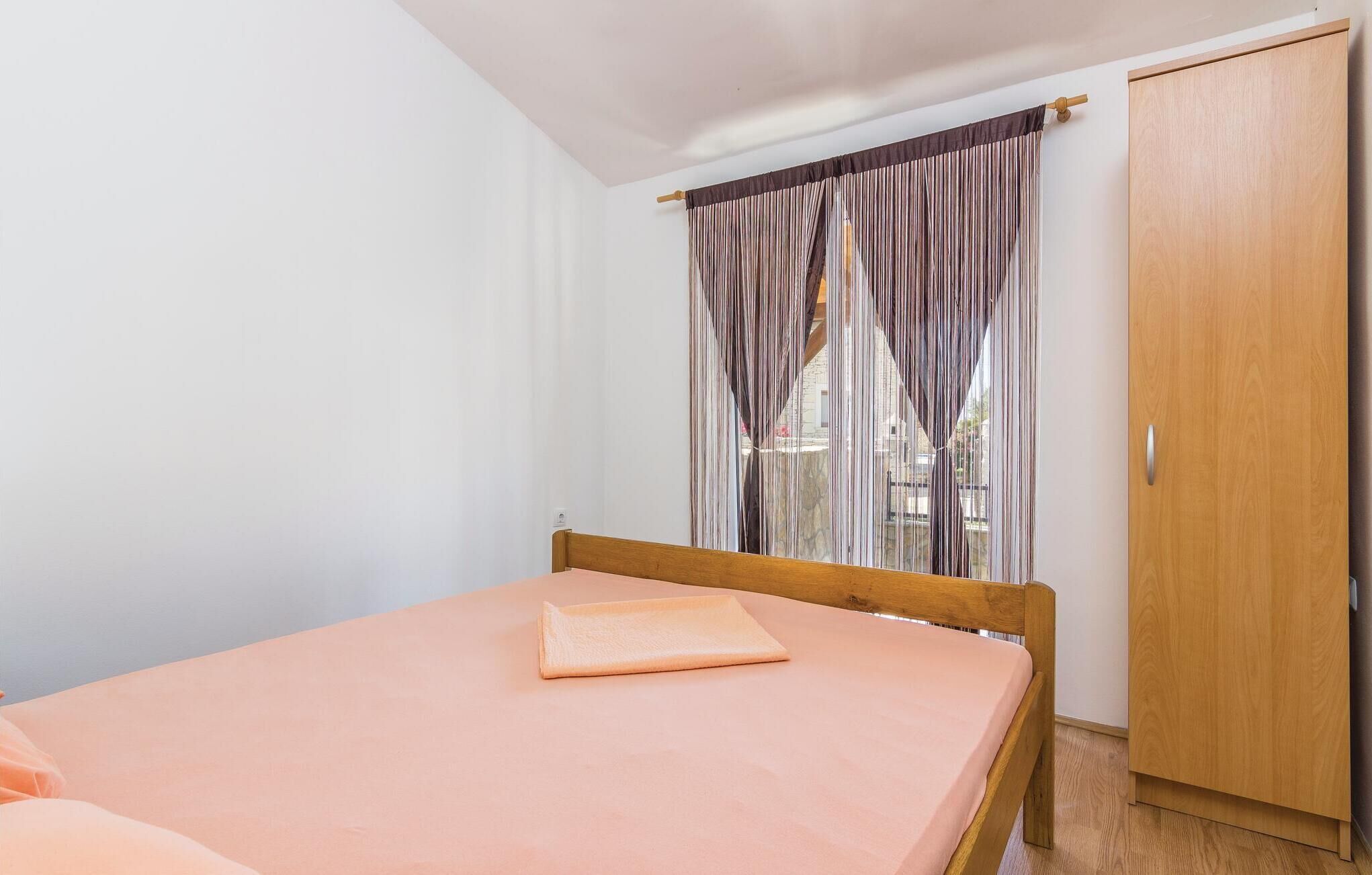 Un dormitorio con una cama individual, un armario de madera y una ventana con cortinas a rayas.