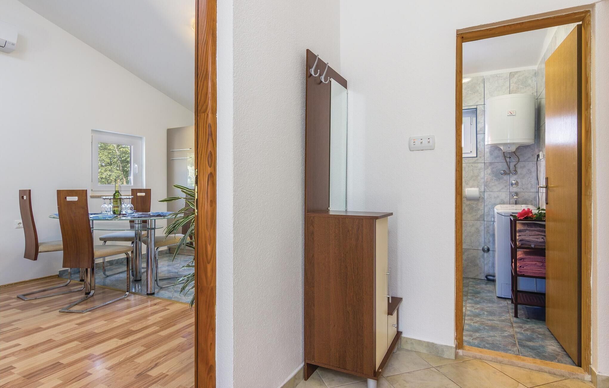 Ein modernes Interieur mit Essbereich, einem Holzkabinett und einem durch eine offene Tür einsehbarer Badezimmer.