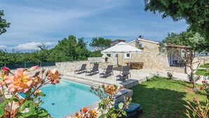Un edificio de piedra con piscina, mobiliario exterior y jardín.