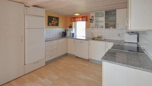 Cozinha com armários brancos, bancada de granito e piso de madeira.
