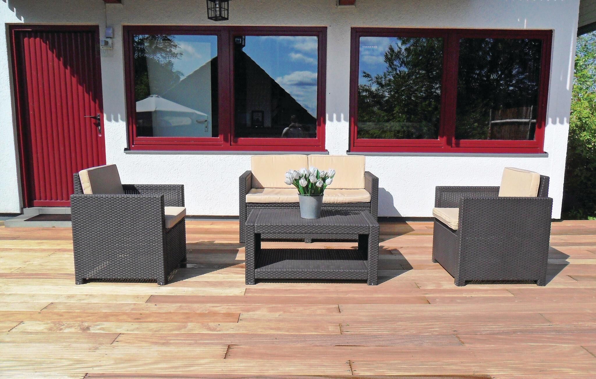 An outdoor seating area with wicker furniture and a central table with a vase of flowers.