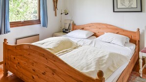 Un letto di legno con biancheria bianca, un comodino con una lampada e un quadro appeso al muro.