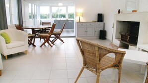 Un espacio habitable amplio con mesa de comedor, sillas, sofá, chimenea y cocina al fondo.