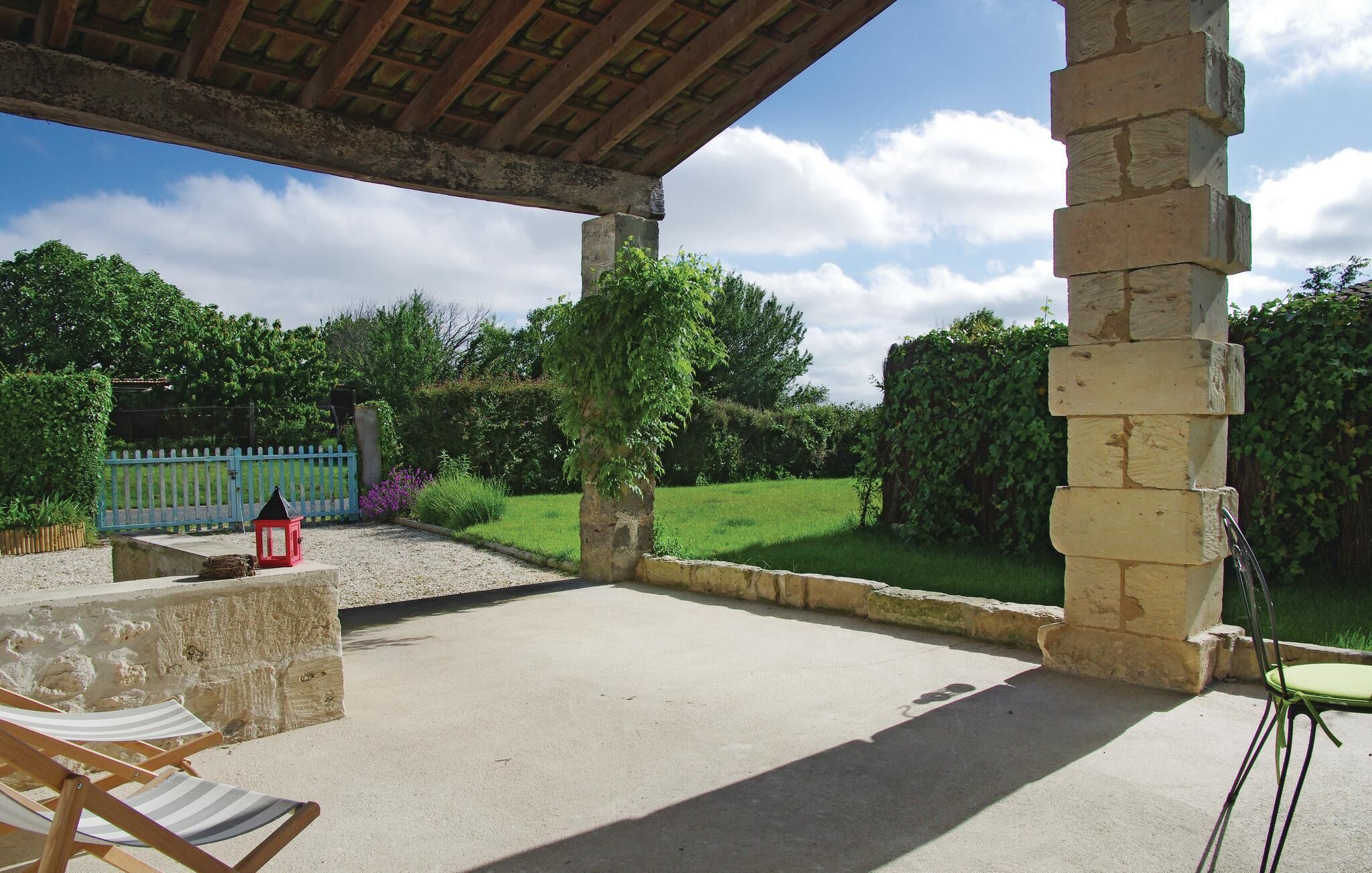 Un patio al aire libre con un banco de piedra, un farol rojo y una cerca azul.
