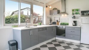 Una cocina moderna con armarios grises, piso a cuadros blanco y negro, lavavajillas, horno y microondas.