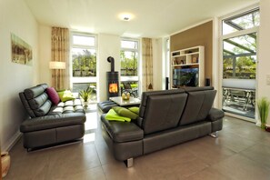 A modern living room with a sofa, a fireplace, and a view of the outdoors.
