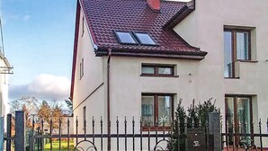 Un bâtiment à deux étages, doté d’un toit en pente, de nombreuses fenêtres et d’une clôture en métal au premier plan.