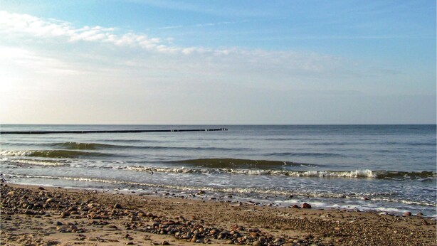 Une plage avec un rivage rocheux et des vagues calmes.