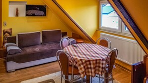 Un salon confortable avec un canapé, une table à manger et des chaises, ainsi qu’une fenêtre donnant sur un beau paysage.