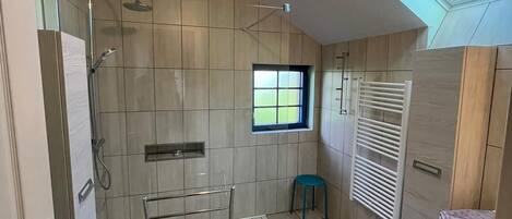 A modern bathroom with a skylight, a shower, a towel rack, and a window.