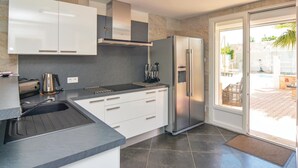 A modern kitchen with white cabinets, a stainless steel refrigerator, and a built-in oven. - Nice home in Le Grau d'Agde (Le Grau d'Agde)