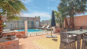 A pool area with lounge chairs, a table, and a pergola. - Nice home in Le Grau d'Agde (Le Grau d'Agde)
