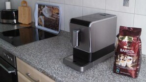 Une cuisine équipée d’une machine à café, d’un grille-pain, d’une planche à découper et d’un sac de grains de café.