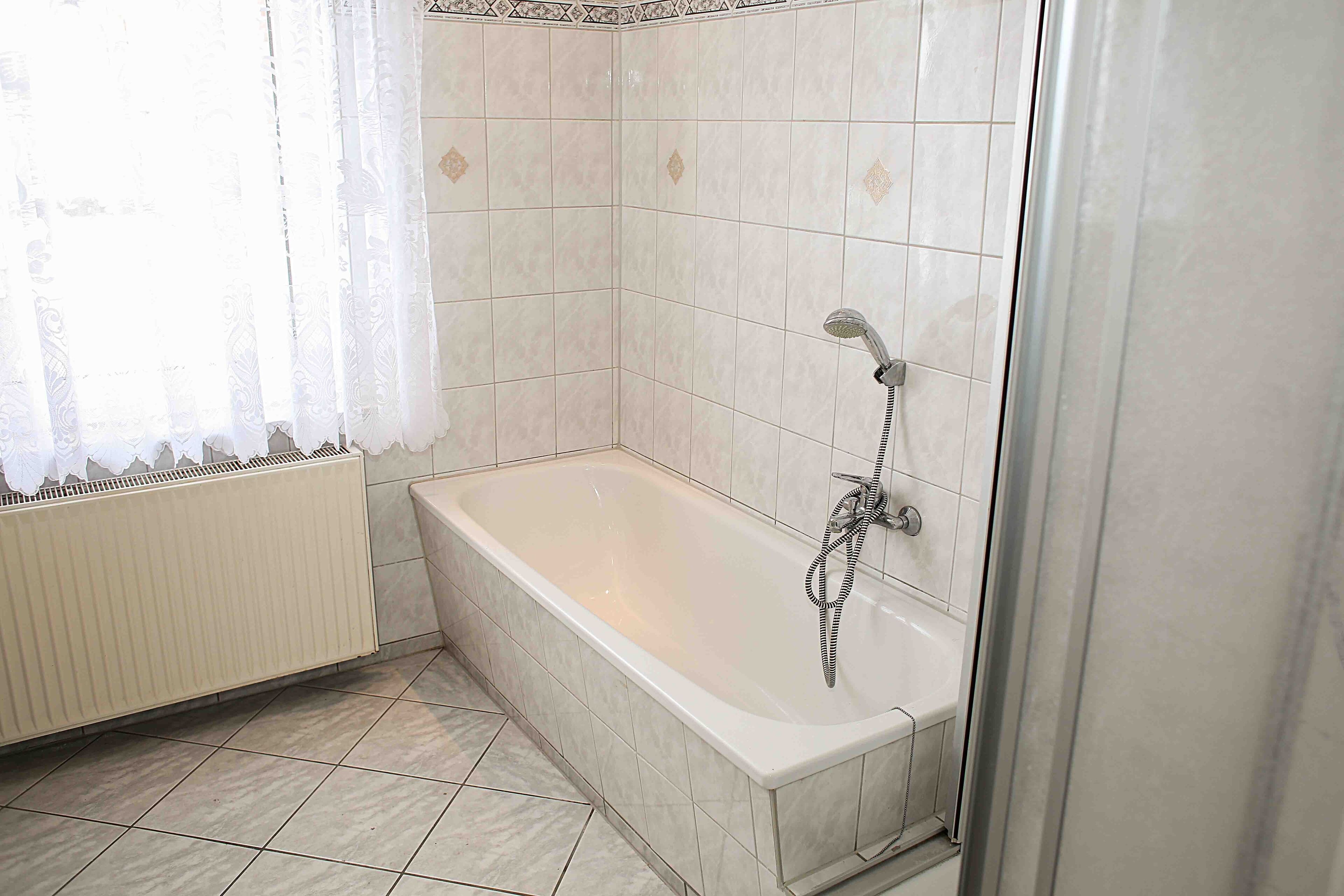 A bathroom with a bathtub, shower, and tiled floor.