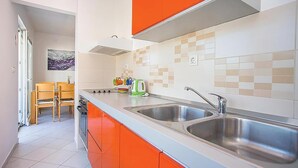 A modern kitchen with two stainless steel sinks, orange cabinets, and a tiled backsplash. - Amazing apartment in Kleke with WiFi (Kleke)