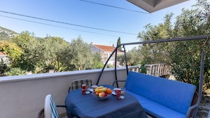 A balcony with a table set for two, a blue sofa, and a swing chair. - Amazing apartment in Kleke with WiFi (Kleke)