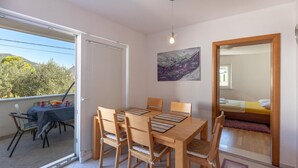 A dining area with a table and chairs, a painting on the wall, and a bed in the adjacent room. - Amazing apartment in Kleke with WiFi (Kleke)